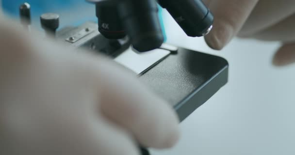 Close up of microscope oculars being directed at a sample on a piece of glass. Close-up shot of sample slide and microscope with metal lens at laboratory. — Stock Video