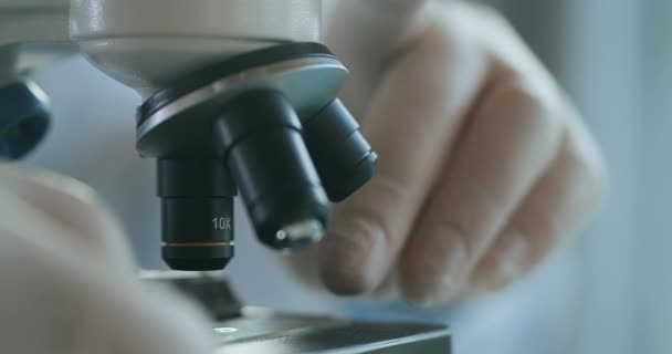 Close up of microscope oculars being directed at a sample on a piece of glass. Close-up shot of sample slide and microscope with metal lens at laboratory. — Stock Video