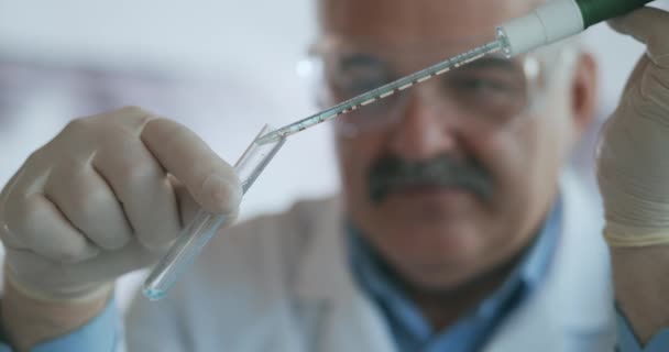 Technik opatrně odkapává roztok z pipety do skleněných zkumavek pro analýzu DNA. Doctor Drips Blue Solution Into Glass Tube, Coronavirus Pandemic, Hands Closeup. — Stock video