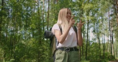 Komik bayan turist ormanda yürüyor ve bir sırt çantasıyla dans ediyor.