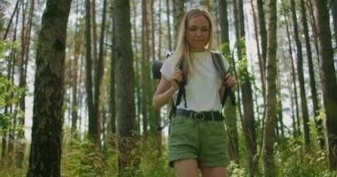 Bir kadının çimler arasında sırt çantasıyla orman yolunda yürüdüğünü gösteren yavaş çekim görüntüleri.