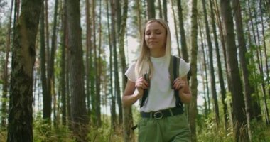 Bir kadının çimler arasında sırt çantasıyla orman yolunda yürüdüğünü gösteren yavaş çekim görüntüleri.