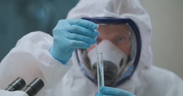 Микробиолог принимает жидкость с опасными бактериями из пробирки на пипетке в лаборатории, работает с химикатами и токсинами, крупным планом — стоковое видео