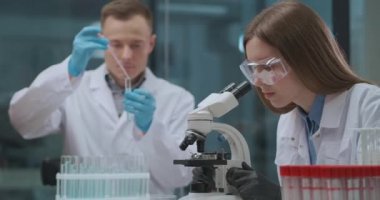 Tıp bilim adamlarından oluşan bir ekip tıbbi laboratuvarda koronavirüsten aşı geliştiriyor. Kadın ve erkek virüs ve bakterileri araştırıyor.