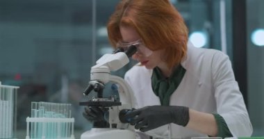 Kadın profesyonel mikrobiyolog laboratuvarda analiz araştırması yapıyor. Mikroskop ve üniversitede genetik laboratuvar araştırması yapıyor.