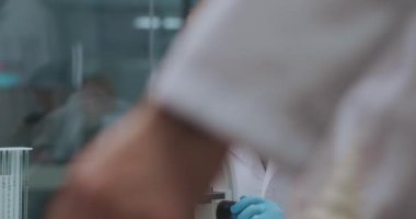 Bilim adamı laboratuvarda koronavirüsten yapılan aşıyı inceliyor. Mikroskop cihazlarını inceliyor.