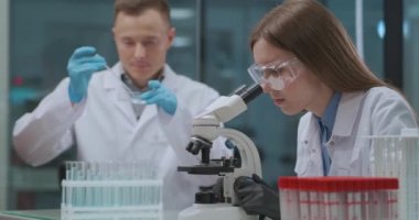 İki bilim adamı tıbbi laboratuvarda biyolojik örnekleri inceliyor. Analizlerle teşhis konuyor. Erkek ve kadın teknisyenler.