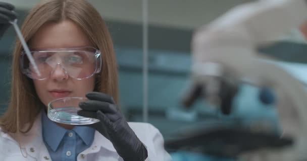 В фармацевтической лаборатории разрабатывают современный препарат от различных заболеваний, женщина-ученый исследует новый образец — стоковое видео