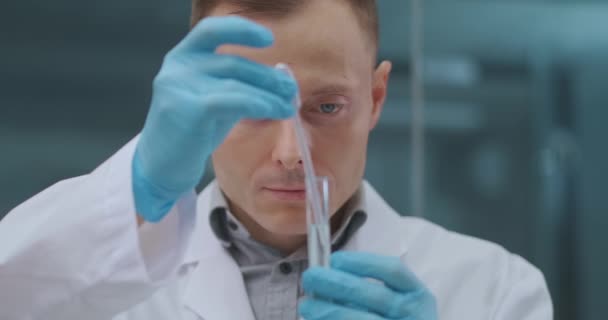 Męski technik laboratoryjny testuje i analizuje nowy lek do leczenia koronawirusów, pobierając próbkę z probówki — Wideo stockowe