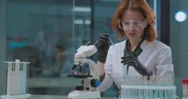 Kadın kimya laboratuvarında çalışıyor, kimyasalları mikroskop ile test ediyor, bilimsel laboratuvar deneyleri ve araştırmaları için.