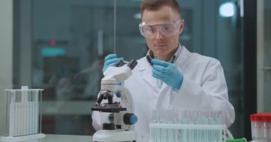 Laboratuvarda COVID-19 testi, erkek teknisyen PCR ve seroloji testleri yapıyor, örnek ve mikroskop tüpleri kullanıyor.