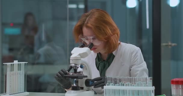 Professionelle Geningenieurin erforscht Analyse im Labor, sucht im Mikroskop, erforscht DNA-Krankheiten — Stockvideo