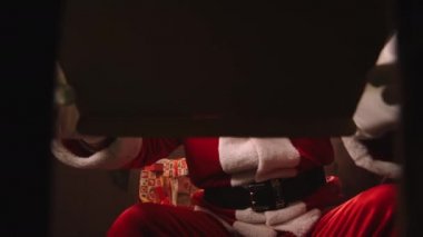  Noel Baba hediyeleri Noel gecesi evde açıyor, oyuncakla birlikte kutuyu açıyor, içine bakıyor, kutudan bakıyor.