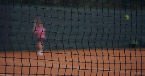 Una joven tenista morena juega una pelota al atardecer en una cancha de tenis. Una mujer juega al tenis profesional y dinámicamente en cámara lenta — Vídeo de stock