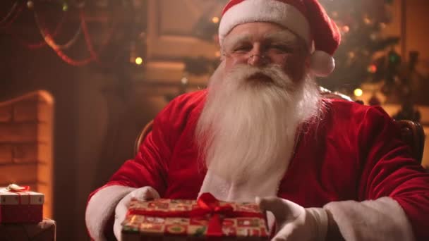 Gentil Père Noël donne cadeau, tenant une boîte à la caméra et souriant amical, portrait de sorcier dans la chambre — Video