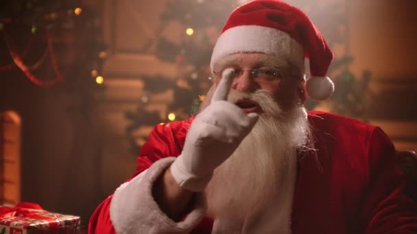 Загадочная атмосфера рождественской ночи, портрет Санта-Клауса в комнате с украшениями, волшебник просит тишину за пальцем жест — стоковое видео