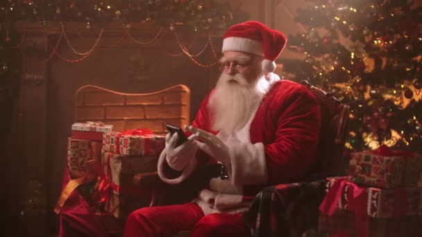 Netter und lustiger Weihnachtsmann nutzt modernes Smartphone mit Internet, surft in sozialen Netzwerken, Porträt des alten Zauberers — Stockvideo