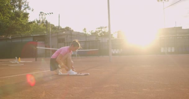 Female tennis player on the court tying her shoelaces — Stock Video