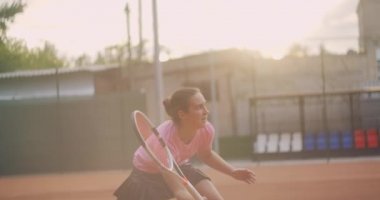 Sahadaki bir bayan tenisçi ağır çekimde topa vuruyor.