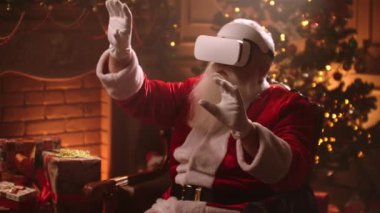 VR kulaklıklı Noel Baba sanal gerçekliğin tadını çıkarıyor, 3 boyutlu videoları izliyor, Xmas akşamında odasında oturuyor.