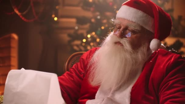 De Kerstman leest een lijst voor van goede kinderen en wensen in zijn woonplaats op de Noordpool, wonder tijdens kerstvakantie — Stockvideo