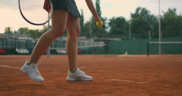 Повільний рух: молода кавказька дівчина-тенісистка, яка грає в теніс під час гри або практики. Гравець у теніс служить при дворі глини. — стокове відео