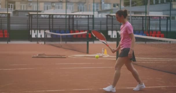 Жінка ходить на тенісному корті з ракеткою і стукає м'ячем на землю. концентрація буде вигравати — стокове відео