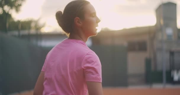 Profesjonalnie wyposażona kobieta mocno bije piłkę tenisową rakietą tenisową. Kobieta tenisistka w akcji podczas gry. Ma na sobie niemarkowe ubranie sportowe.. — Wideo stockowe