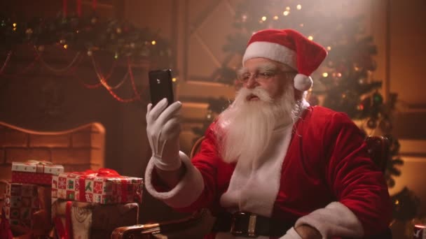 Der alte Weihnachtsmann nutzt die moderne Online-Kommunikation per Internet, telefoniert an den Weihnachtsfeiertagen per Smartphone — Stockvideo
