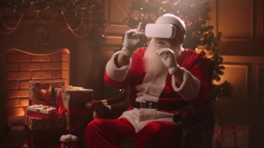Noel Baba HMD ekranı kullanıyor, elle yönetiyor, Xmas 'daki evinde koltuğunda oturuyor.