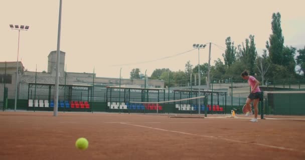 Szoros felvétel női lábakról sportcipőben és protézis a lábán, ahogy teniszlabdákat vesz fel a teniszpályáról. — Stock videók