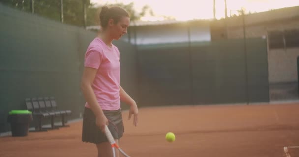 女网球选手在日落时在球场上的一名女网球选手，比赛后疲惫地向前看，在一场艰苦的比赛后专心工作 — 图库视频影像