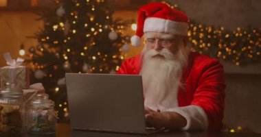 Neşeli Noel Baba dizüstü bilgisayarda çalışıyor. Noel Baba dizüstü bilgisayar kullanıyor, yakın plan..