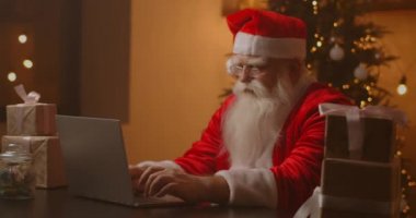 Neşeli Noel Baba dizüstü bilgisayarda çalışıyor. Noel Baba dizüstü bilgisayar kullanıyor, yakın plan..