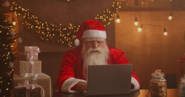 Gerçek Noel Baba çocuklarla iletişim kurmak için yeni teknolojiler kullanır. Posta ya da dilek listesi alır. Mutlu bir şekilde dizüstü bilgisayarda çalışıyor ve gülümsüyor. Sandalyesinde şömine ve Noel Ağacı ile oturuyor.