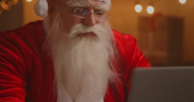 Gerçek Noel Baba çocuklarla iletişim kurmak için yeni teknolojiler kullanır. Posta ya da dilek listesi alır. Mutlu bir şekilde dizüstü bilgisayarda çalışıyor ve gülümsüyor. Sandalyesinde şömine ve Noel Ağacı ile oturuyor.