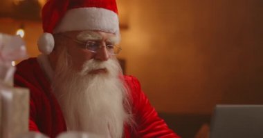 Neşeli Noel Baba dizüstü bilgisayarda çalışıyor. Noel Baba dizüstü bilgisayar kullanıyor, yakın plan..