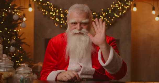 Headshot Ser på kameraet Glade gamle skæggede Santa Claus iført kostume og vinke hånd video opkald i zoom, optagelse video Glædelig jul hilsen, ansigt kamera udsigt. – Stock-video