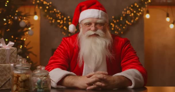 Close-up van grijsharige Kerstman in bril kijkend naar camera. Hoofdfoto portret van grappige oude soort bebaarde Kerstman gezicht. Sint Nicolaas groet op Vrolijk Kerstfeest — Stockvideo