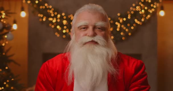 Detailní záběr šedovlasého Santa Clause v brýlích při pohledu do kamery. Hlavonosný portrét legračního starého vousatého Santa Clause. Svatý Mikuláš pozdrav na Veselé Vánoce — Stock video
