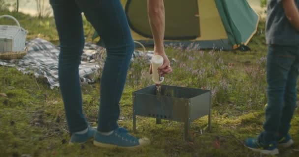 Picknick im Zeltlager, Mann und kleiner Junge bereiten Holzgrill zum Kochen vor, Familie ruht sich im Wald aus — Stockvideo