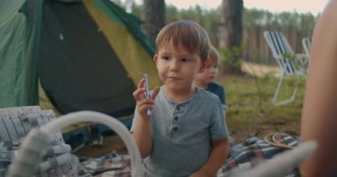 Anaokulu çocuğu aile pikniğinde katlanan bıçakla oynuyor. Ormanda aile için kamp kuruyor.