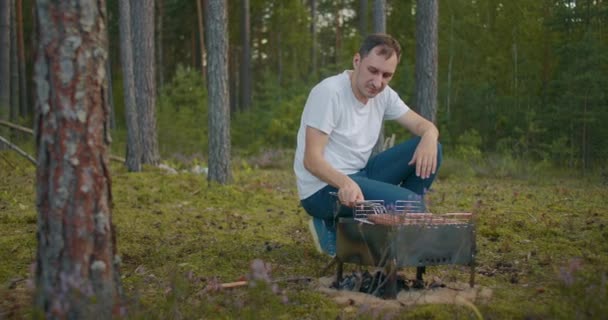 Homem adulto está grelhando salsichas na floresta, piquenique na natureza no fim de semana de verão ou férias, descansando e relaxando — Vídeo de Stock
