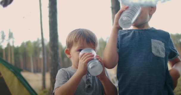 Dua anak laki-laki sedang minum air, saudara laki-laki sedang beristirahat di perkemahan dengan orang tua, keluarga bepergian di alam — Stok Video