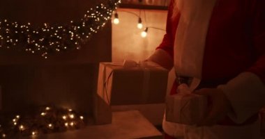Noel Baba 'nın elinin yakın çekimi çocuklar için Noel ağacının altına hediyeler getirir. Noel gecesi çocuklara hediyeler ver. Noel Baba Noel ağacının altına hediye koyar.