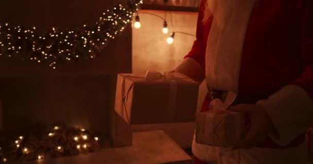 Cerca - hasta de la mano de Santa: trae regalos bajo el árbol de Navidad para los niños. Dar regalos a los niños en la noche de Navidad. Santa pone un regalo bajo el árbol de Navidad — Vídeos de Stock