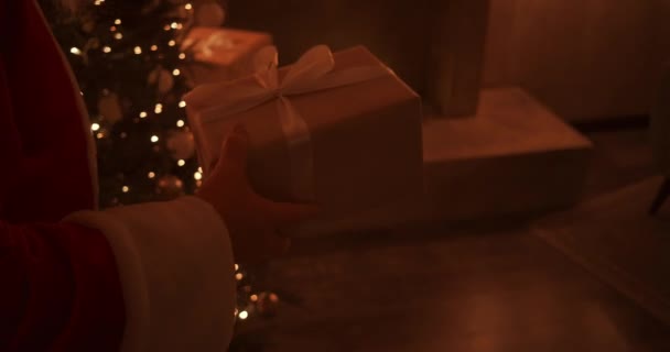 Papai Noel traz um presente para as crianças na noite de Natal e coloca-o perto da árvore de Natal na casa das crianças. a câmera monitora a entrega do presente sob a árvore — Vídeo de Stock