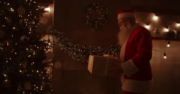 In der Weihnachtsnacht bringt der Weihnachtsmann Geschenke nach Hause, während alle schlafen. Weihnachtsmann legt Geschenke unter dem Weihnachtsbaum im geschmückten Haus ab — Stockvideo