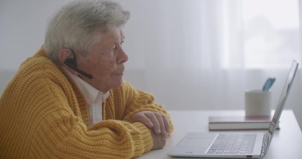 Mujer de edad avanzada están utilizando el ordenador portátil para hacer videollamadas haciendo gestos que muestran los pulgares hacia arriba gesto de la mano en el interior. Mujer de edad y los dispositivos modernos concepto. — Vídeos de Stock