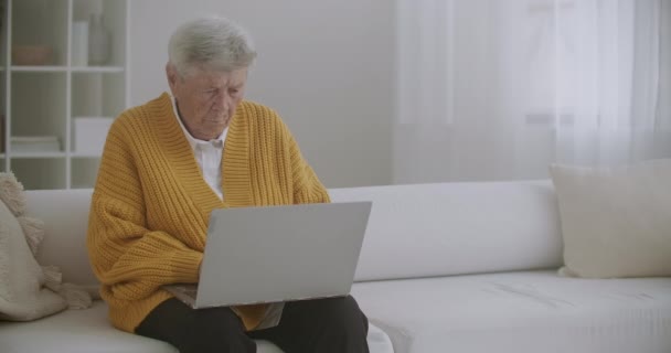 Anciana madura mayor escribiendo un mensaje en el teclado, webinar en línea en el ordenador portátil de trabajo remoto o aprendizaje a distancia social desde casa. Mujer de negocios de los años 60-80 — Vídeo de stock